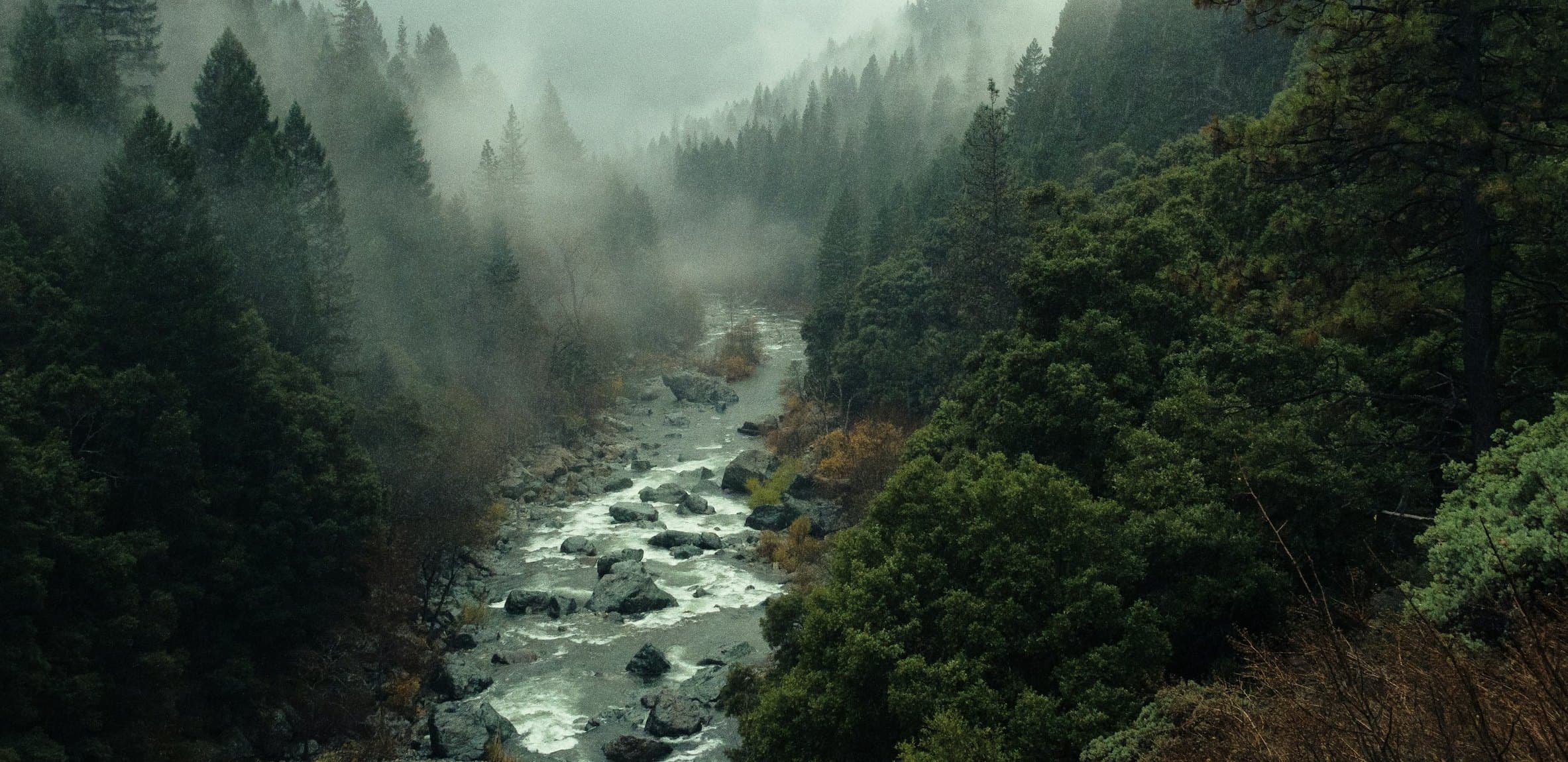 River running over rocks through a misty forest valley